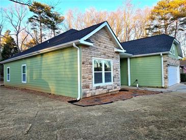 Charming home displaying a harmonious blend of stone and green siding, complemented by a dark roof and manicured lawn at 6022 Fieldcrest Dr, Morrow, GA 30260