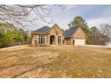 Charming brick home featuring an attached two car garage and a well manicured front lawn and garden at 2915 Pruitt Rd, Cumming, GA 30041