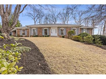 Charming brick home featuring gray shutters and manicured front yard landscaping at 4755 Huntley Dr, Atlanta, GA 30342