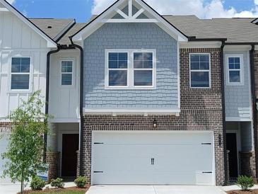 Charming townhome featuring a two-car garage, brick accents, and light blue shingle siding at 541 Tuskegee St # 49, Mcdonough, GA 30253