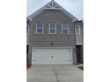 Two car garage beneath a two-story townhome with grey brick and a peak roof at 549 Tuskegee St, Mcdonough, GA 30253