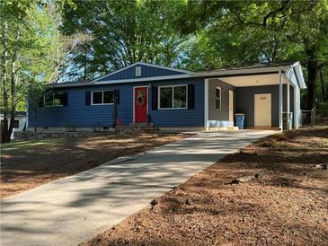 Charming blue home featuring a long driveway, red front door, and a covered carport at 1504 Sycamore Nw Dr, Kennesaw, GA 30152