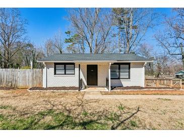 Charming single-story home featuring a white brick exterior, dark trim, and well-maintained landscaping at 105 Huskins Rd, Canton, GA 30115