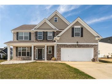 Charming two-story home with stone accents, attached garage, inviting porch and manicured lawn at 1009 S Creek Dr, Villa Rica, GA 30180