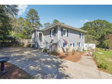 Charming two-story home with gray siding, blue shutters, and a spacious front yard with a long driveway at 4828 Lakewood Dr, Acworth, GA 30101