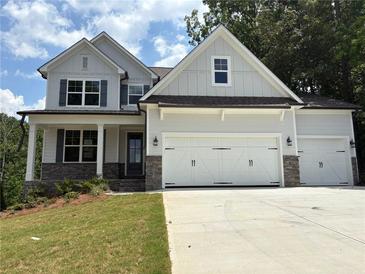 Charming two-story home with a three-car garage, stone accents, and a well-manicured lawn at 385 Riverwood Pass, Dallas, GA 30157
