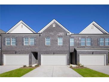 Charming townhomes featuring a gray brick facade, white trim, and attached garages at 228 Epping Street # 8, Stockbridge, GA 30281