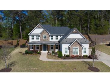Beautiful two-story home featuring stone accents, a welcoming front porch, and a well-maintained landscaped yard at 6650 Canyon Cv, Cumming, GA 30028