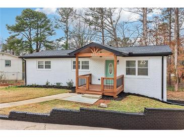 Charming renovated single-story home with brick exterior, wood porch and turquoise door at 5901 Miller Rd, Austell, GA 30106