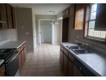 A kitchen with tile floors, wood cabinets, white countertops, and stainless steel double basin sink at 10 Oak Wood Ln, Covington, GA 30016