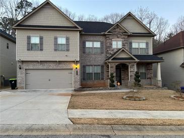 Charming two-story home featuring a mix of stone and siding, with a two-car garage and manicured front yard at 5215 Tye Trl, Fairburn, GA 30213