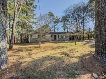Charming single-story home with grey brick facade, mature trees, and a spacious front yard at 1894 Dogwood Ct, Snellville, GA 30078