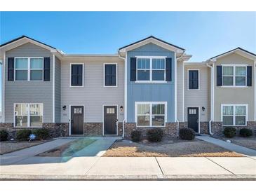 View of townhomes with varying exterior colors, brick foundations, dark shutters, and well-manicured landscaping at 402 Whippet St, Union City, GA 30291