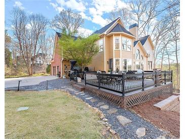 A sprawling two-story home with a large deck, a well-manicured lawn, and a beautiful stone pathway at 650 Vinings Estates Se Dr, Mableton, GA 30126