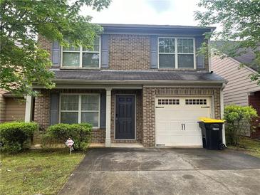 Charming two-story brick home with gray shutters, well-manicured lawn, and attached one-car garage at 312 Lauren Dr, Fairburn, GA 30213