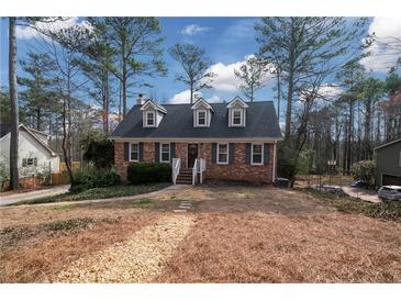 Charming brick home with dormer windows and landscaped front yard surrounded by mature trees on a sunny day at 1835 Tree Top Way, Marietta, GA 30062