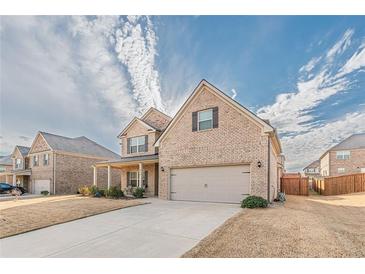 Charming two-story brick home featuring an attached two-car garage and covered front porch at 879 Tranquil Way, Hampton, GA 30228