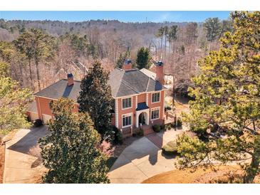 Stately red brick home featuring manicured grounds, mature trees, and driveway at 3832 Wesley Chapel Rd, Marietta, GA 30062