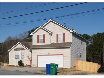 Charming two-story home features a large garage, neutral siding, red window trim, and a well-maintained yard at 5546 Wellborn Creek Dr, Lithonia, GA 30058