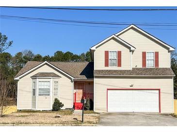 Charming two-story home with a well-manicured lawn, red door, and attached garage at 5546 Wellborn Creek Dr, Lithonia, GA 30058