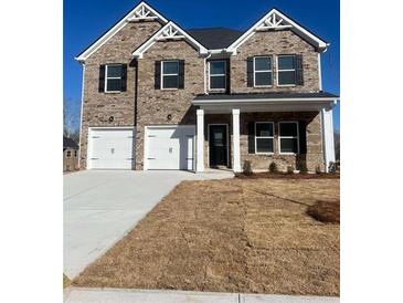 Two-story brick home featuring a two-car garage and a covered porch at 654 Egrets Lndg, Covington, GA 30014