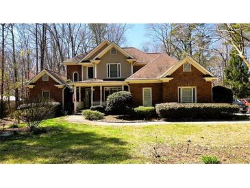 Charming two-story brick home with a well-manicured front yard, a covered porch, and mature trees at 1811 Mcconnell Rd, Grayson, GA 30017