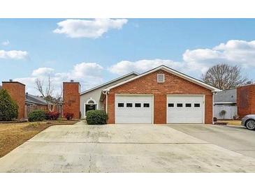 Charming brick home featuring a two-car garage and a well-maintained front yard at 135 Wilbanks Dr, Fayetteville, GA 30215