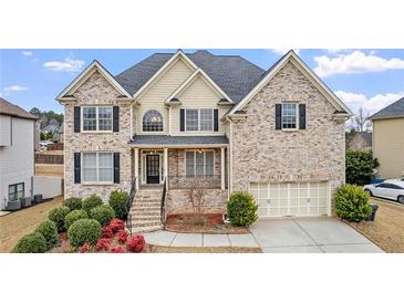 Two story home with a brick front, black shutters, two car garage, and manicured lawn at 1859 Mapmaker Dr, Dacula, GA 30019