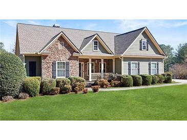 Charming home featuring stone accents, green siding, lush lawn, and well-maintained landscaping at 1656 Maes Overlook, Loganville, GA 30052