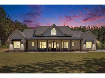 Stunning white farmhouse exterior featuring a large porch and professionally landscaped front yard, perfect for southern living at 2925 Old Broadnax Mill Rd, Loganville, GA 30052
