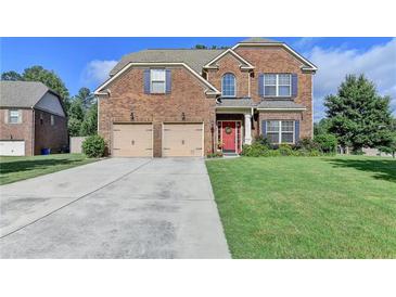 Inviting two-story brick home featuring a red front door, attached two-car garage and well-maintained lawn at 1211 Chapel Estates Way, Dacula, GA 30019
