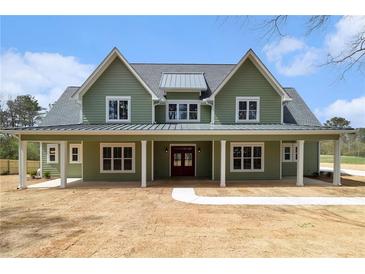 Charming two-story home with a covered porch, green siding, and a welcoming red front door at 529 Claude Scott Rd, Canton, GA 30115