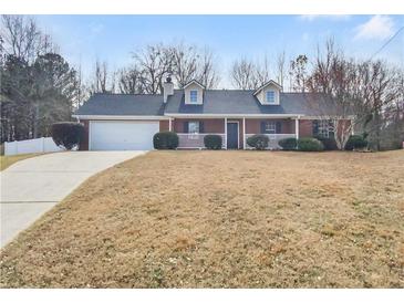 Charming brick home features a well-manicured lawn, attached garage, and inviting front porch at 12 Bonnie Glen Ln, Hampton, GA 30228