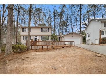 Charming two-story home featuring a wooden deck, attached garage, and beautiful landscaping at 1731 Fieldgreen Overlook, Stone Mountain, GA 30088