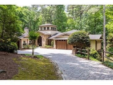 Charming stone and siding home with a beautiful turret and a brick driveway amidst lush greenery at 4421 Paradise Cir, Vinings, GA 30339