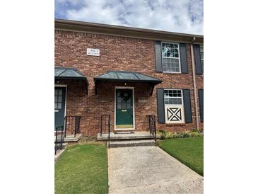 Inviting brick townhouse with a green door, a covered entry, and a well-manicured lawn at 5674 Kingsport Dr # 4, Atlanta, GA 30342