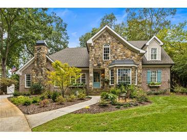 Charming stone home featuring a beautiful stone chimney, well-manicured landscaping, and a quaint front porch at 1993 Mount Vernon Pl, Dunwoody, GA 30338