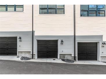 View of attached garages with black doors and light fixtures in a modern townhome exterior at 728 Se Eloise Se Way, Atlanta, GA 30312