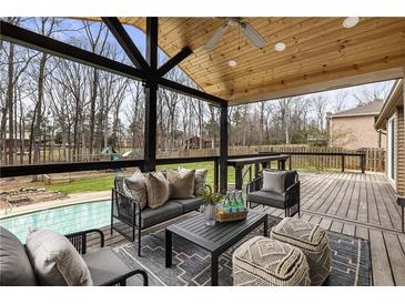 Inviting covered deck with a seating area, stylish furniture, ceiling fan, and views of the lush backyard and sparkling pool at 330 Chaffin Ridge Ct, Roswell, GA 30075