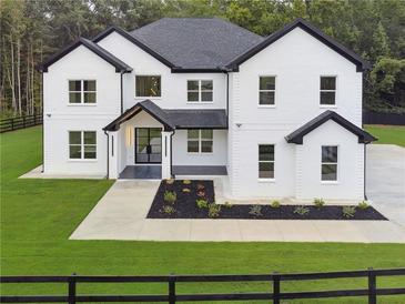 A beautiful two-story white brick home featuring black trim, black roof and lush landscaping at 3165 Hall Rd, Dacula, GA 30019