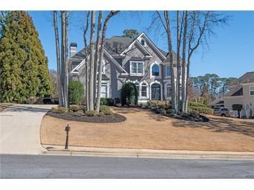 Stately gray two-story home featuring a manicured lawn and mature trees at 6305 Deerwoods Trl, Alpharetta, GA 30005