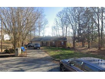 Charming brick home features an attached garage and inviting front yard with mature trees at 1564 Mill Run Ct, Lawrenceville, GA 30046