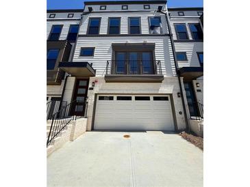 Exterior of a townhome featuring a two-car garage and a second-story balcony at 1113 Rivard Nw Cir, Atlanta, GA 30318