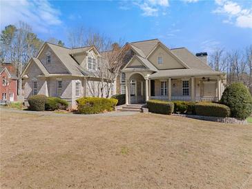 Stunning brick home featuring manicured landscaping, a covered porch, and classic architectural details at 1348 Ewing Creek Dr, Dacula, GA 30019