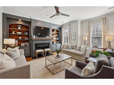 Inviting living room with custom built-ins, fireplace, ceiling fan, and neutral decor at 1205 New Haven Ct, Roswell, GA 30075