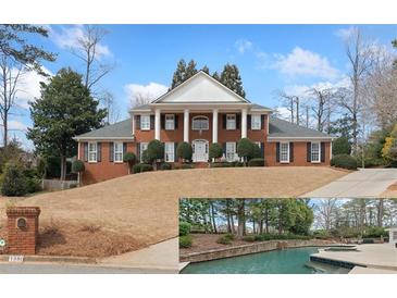 Stately red brick home featuring white columns, black shutters, a well manicured yard, and a custom in ground pool at 1380 Tennis Court Pl, Roswell, GA 30075