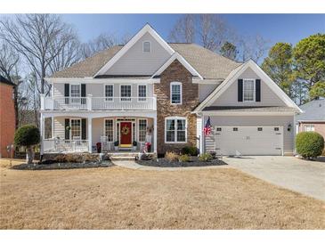 Charming two-story home with a stone accent wall, covered porch and a well-manicured lawn at 5945 Masters Club Dr, Suwanee, GA 30024