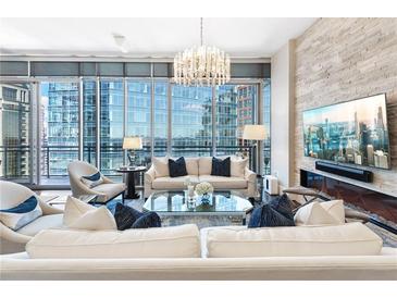 Bright living room with city views, modern chandelier, and stone accent wall with a fireplace at 1065 Peachtree Ne St # 3105, Atlanta, GA 30309