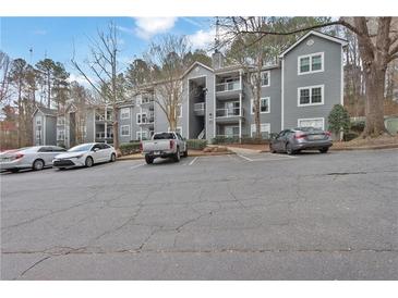 View of gray condo building with multiple balconies and ample parking spaces available for residents and visitors alike at 4206 Santa Fe Pkwy, Atlanta, GA 30350