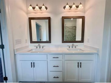 Modern bathroom with double vanity, white cabinets, quartz countertop, wood-framed mirrors, and stylish lighting at 532 Healy Dr # 70, Cumming, GA 30040